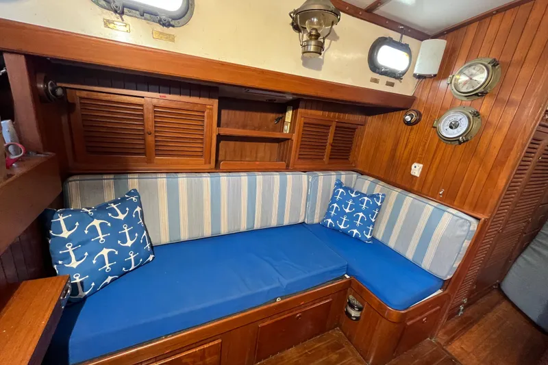 Slide: The Image of Cozy 1982 Tayana 37 yacht interior with nautical-themed cushions and wooden paneling. - 48