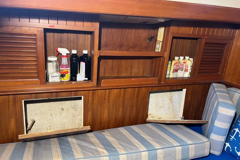 Slide: The Image of Interior of 1982 Tayana 37 sailboat with wooden shelves and cleaning supplies. - 50