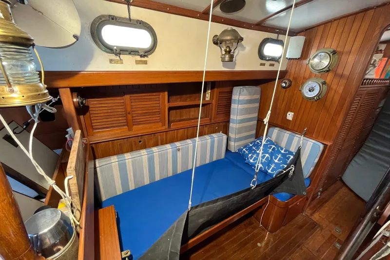 Slide: The Image of 1982 Tayana 37 sailboat interior with wooden paneling, blue cushions, and nautical decor. - 52
