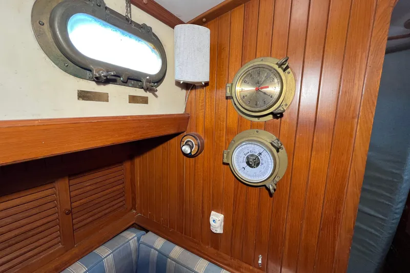 Slide: The Image of Interior of 1982 Tayana 37 sailboat with wooden paneling, porthole, clock, and barometer. - 53