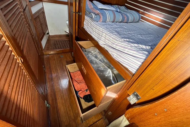Slide: The Image of 1982 Tayana 37 interior with wooden flooring, bed, and open storage drawers. - 56