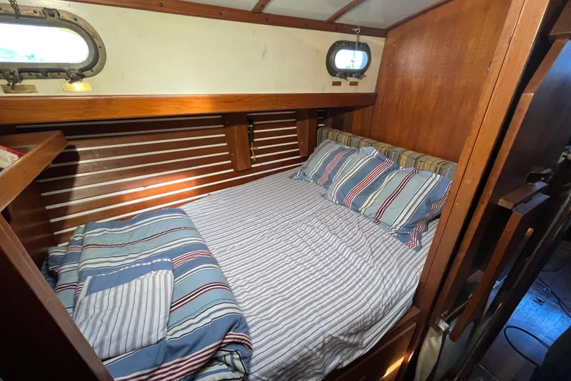 Slide: The Image of Cozy cabin interior of 1982 Tayana 37 sailboat with striped bedding and wooden accents. - 57