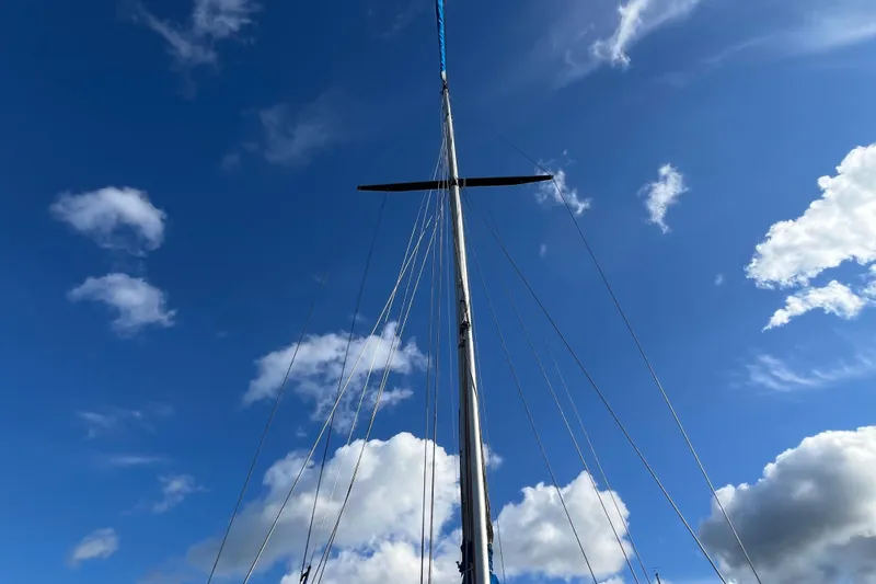 Slide: The Image of Mast of 1982 Tayana 37 sailboat against a bright blue sky with clouds. - 7