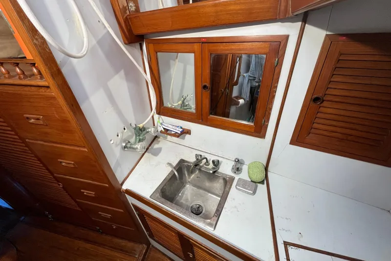 Slide: The Image of 1982 Tayana 37 yacht bathroom with wooden cabinets, mirror, and stainless steel sink. - 70