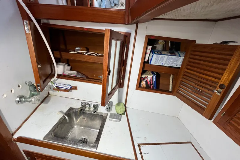 Slide: The Image of 1982 Tayana 37 yacht interior with sink, wooden cabinets, and storage space. - 72