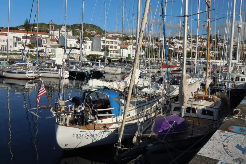 Slide: The Image of 1982 Tayana 37 sailboat docked in a scenic marina with surrounding buildings. - 78