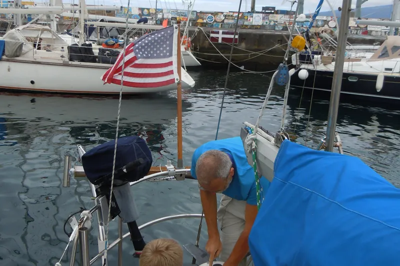 Slide: The Image of Man on 1982 Tayana 37 sailboat in marina, with American flag displayed. - 80