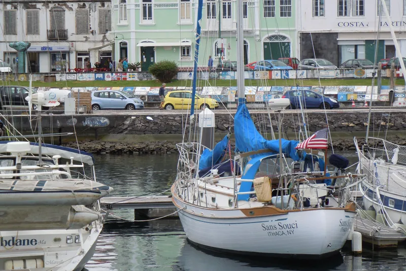 Slide: The Image of 1982 Tayana 37 sailboat docked in a picturesque marina with colorful buildings. - 81