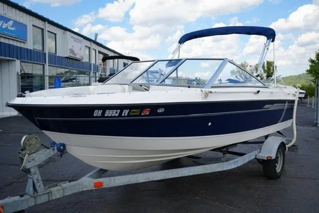 The Image of 2006 Bayliner 195 Classic boat on trailer, parked outdoors near a building. - 1