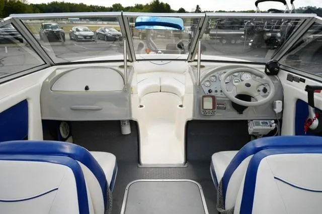 Slide: The Image of 2006 Bayliner 195 Classic boat interior with blue and white seating, dashboard, and steering wheel. - 12