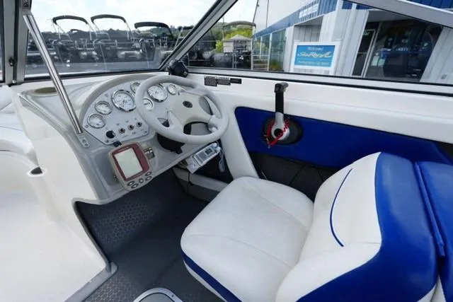 Slide: The Image of 2006 Bayliner 195 Classic boat interior with white and blue seating, steering wheel, and dashboard. - 9