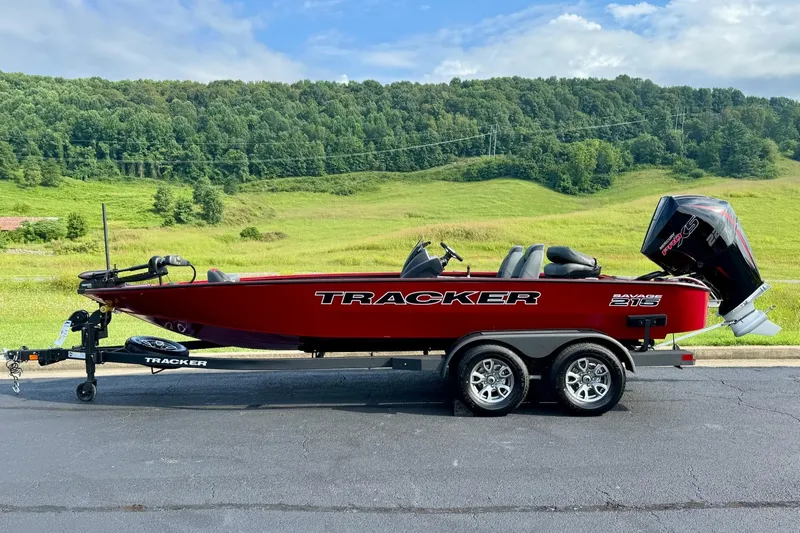 The Image of 2026 Tracker Savage 215 boat on trailer, set against a lush green landscape. - 0