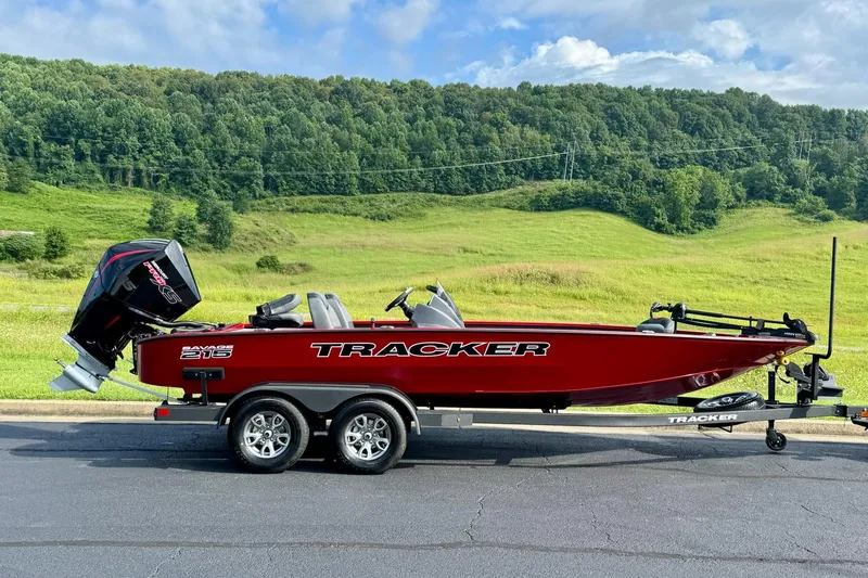 Slide: The Image of 2026 Tracker Savage 215 boat on trailer, parked with scenic green hills in background. - 2