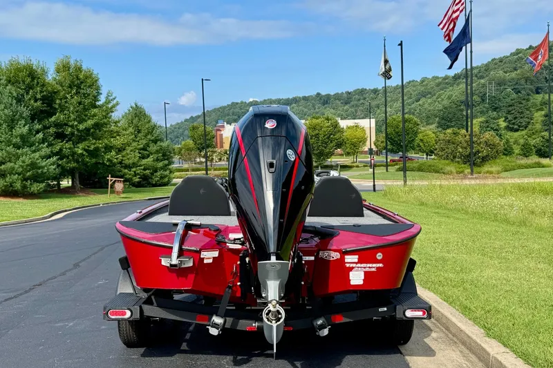 Slide: The Image of 2026 Tracker Savage 215 boat on trailer, parked near flags and greenery. - 3