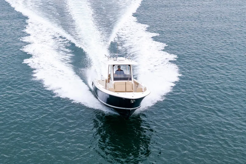 Slide: The Image of 2019 Pursuit S 288 Sport boat cruising on open water, city skyline in background. - 13