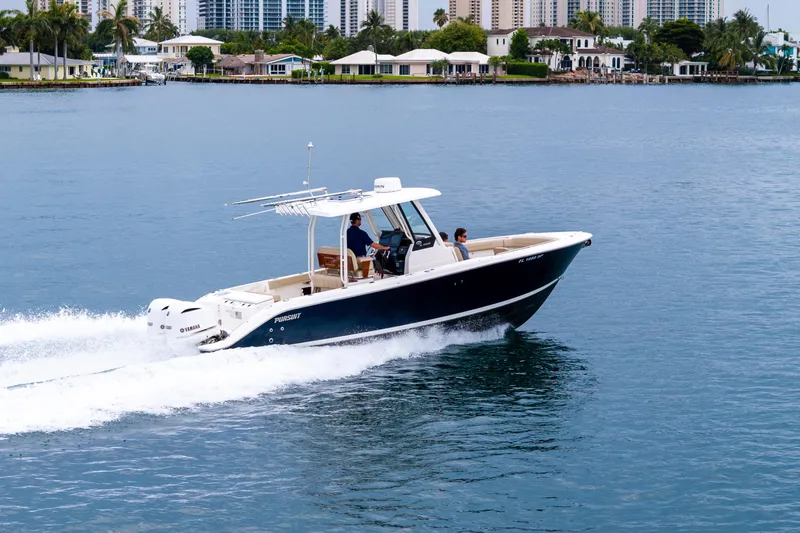 Slide: The Image of 2019 Pursuit S 288 Sport boat on calm water with city skyline in background. - 19
