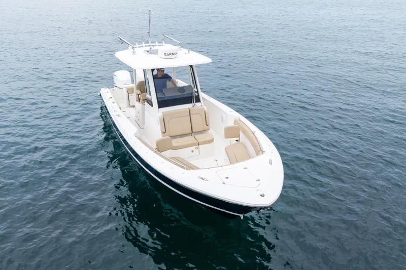 Slide: The Image of 2019 Pursuit S 288 Sport boat helm with navigation screens, steering wheel, and ocean view. - 23