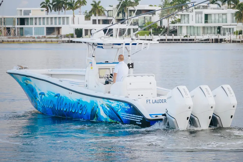 Slide: The Image of 2007 Yellowfin 36 Offshore boat with vibrant graphics, cruising near modern waterfront homes. - 7