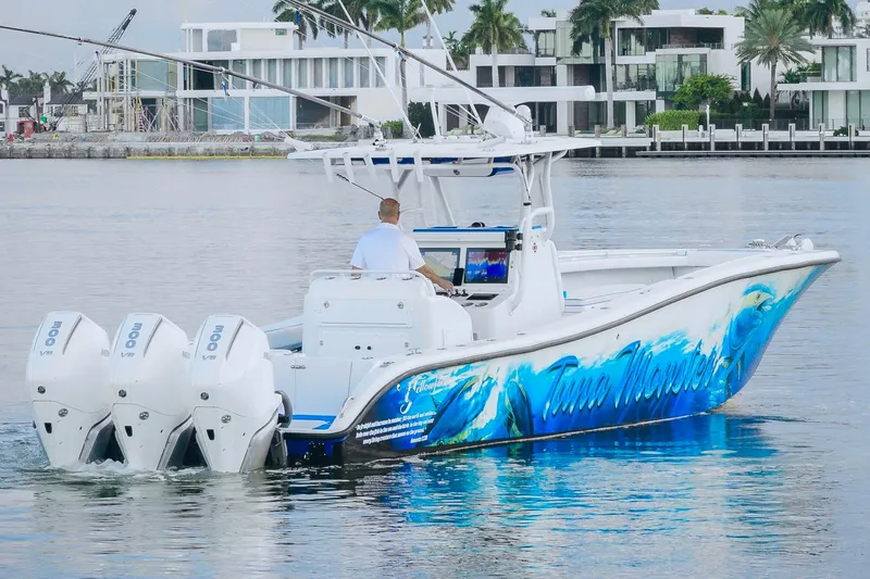 Slide: The Image of 2007 Yellowfin 36 Offshore boat with vibrant graphics and triple outboard motors on calm water. - 8