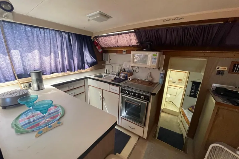Slide: The Image of 1969 Chris-Craft 47 Commander kitchen interior with stove, sink, and blue curtains. - 19