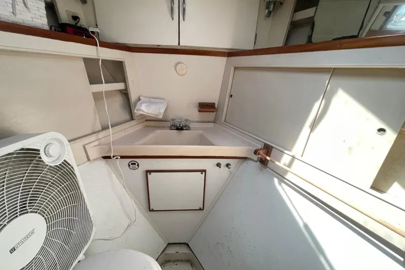 Slide: The Image of 1969 Chris-Craft 47 Commander bathroom with sink, fan, and storage cabinets. - 31