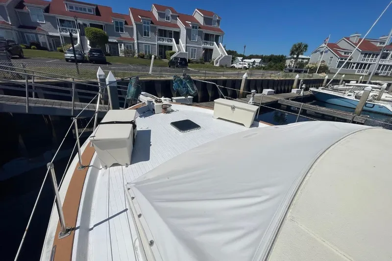 Slide: The Image of 1969 Chris-Craft 47 Commander yacht docked near waterfront homes on a sunny day. - 48