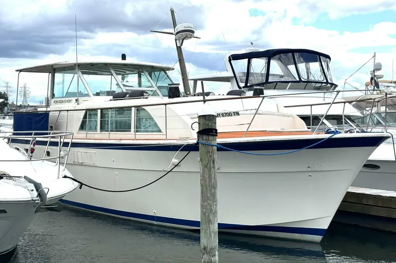 The Image of 1972 Hatteras 43DC yacht docked at marina under cloudy sky. - 1