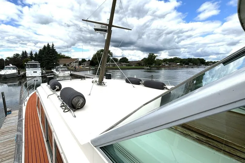Slide: The Image of 1972 Hatteras 43DC yacht docked by a scenic waterfront under cloudy skies. - 13