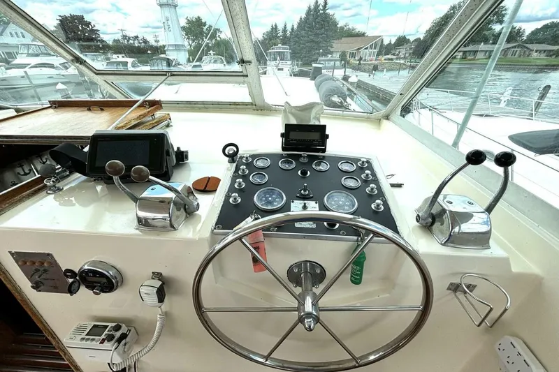 Slide: The Image of 1972 Hatteras 43DC yacht helm with steering wheel, gauges, and controls in a marina setting. - 22