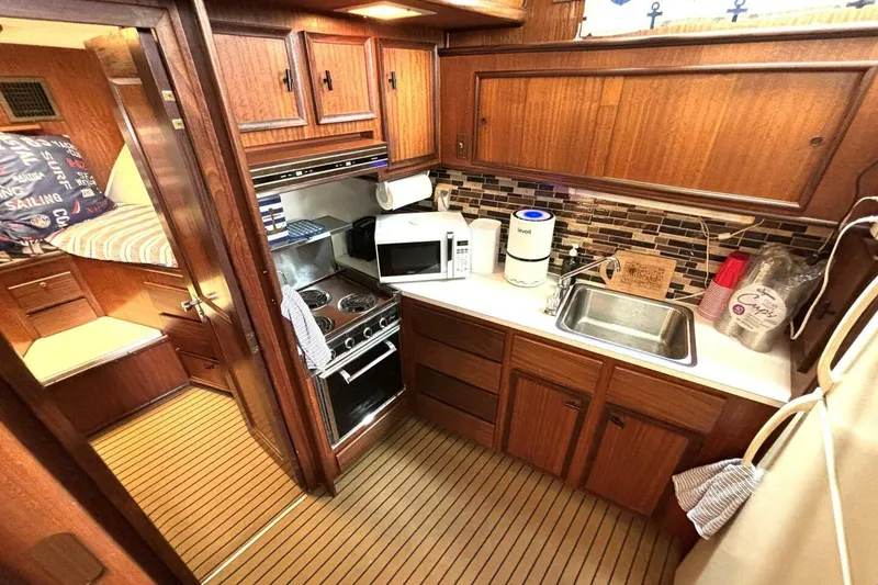 Slide: The Image of 1972 Hatteras 43DC yacht kitchen with wood cabinetry, stove, microwave, and sink. - 31