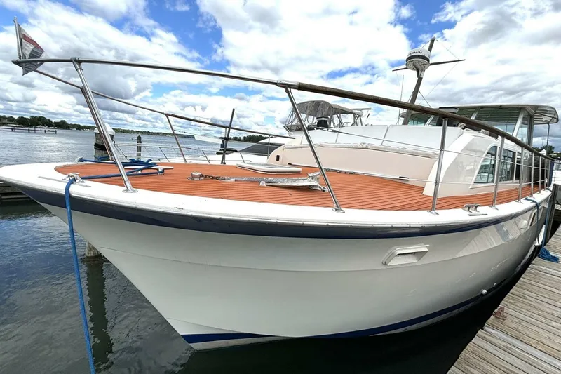 Slide: The Image of 1972 Hatteras 43DC yacht docked, featuring sleek design and wooden deck under cloudy sky. - 4
