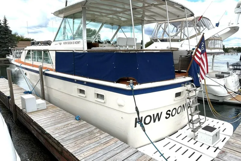 Slide: The Image of 1972 Hatteras 43DC yacht docked, featuring a blue canopy and American flag. - 5