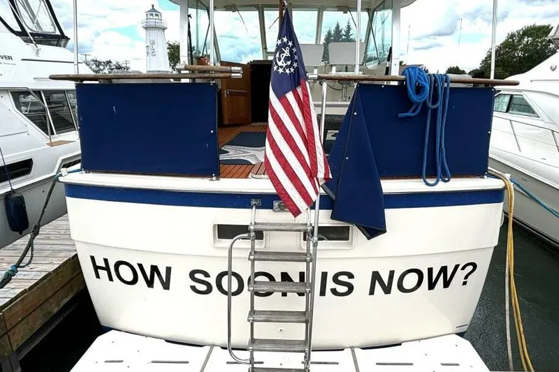 Slide: The Image of 1972 Hatteras 43DC boat with "HOW SOON IS NOW?" text, docked with American flag. - 6