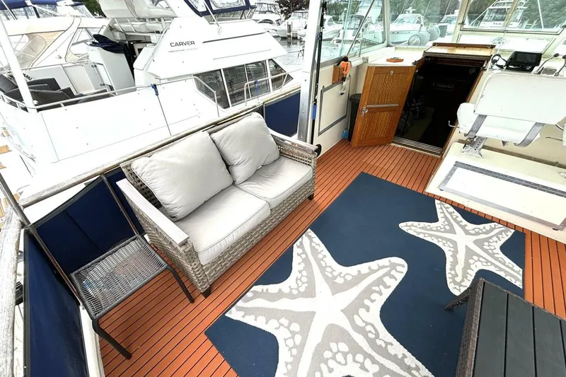 Slide: The Image of 1972 Hatteras 43DC yacht deck with wicker seating, starfish-patterned rug, and wooden flooring. - 9