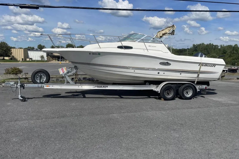 The Image of 2002 Wellcraft 24 Walkaround boat on trailer under a clear blue sky. - 1