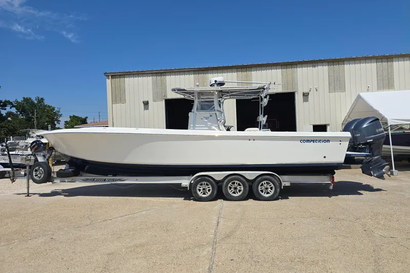 Slide: The Image of 2007 Competition 31 boat on trailer, parked outside a warehouse under clear blue sky. - 27