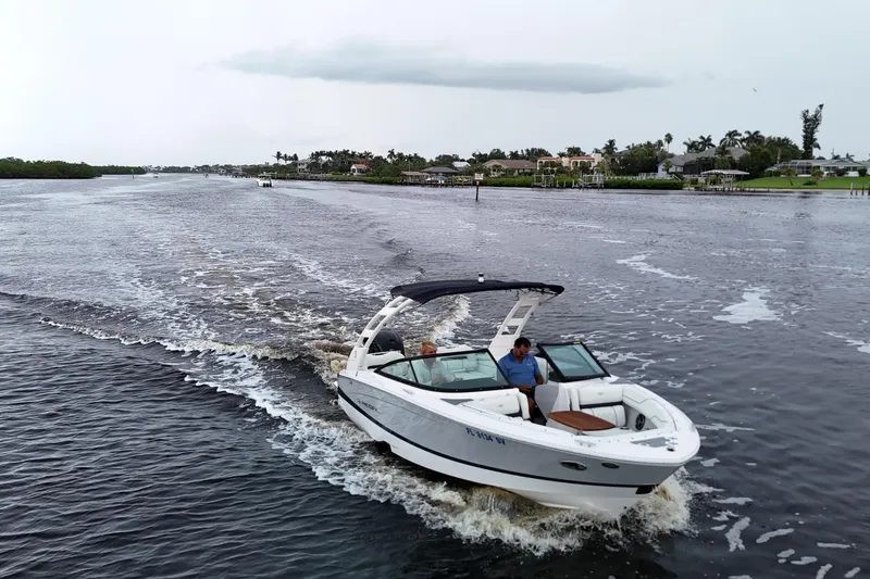The Image of 2021 Regal LX2 boat cruising on a scenic waterway with lush greenery. - 0