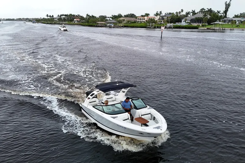 Slide: The Image of 2021 Regal LX2 boat cruising on a scenic waterway with lush greenery. - 1