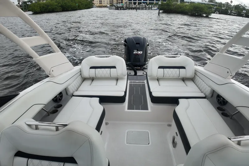 Slide: The Image of 2021 Regal LX2 boat interior with white seating and powerful outboard motor on water. - 12