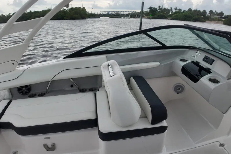 Slide: The Image of 2021 Regal LX2 boat interior with sleek seating and modern dashboard on a scenic waterway. - 20
