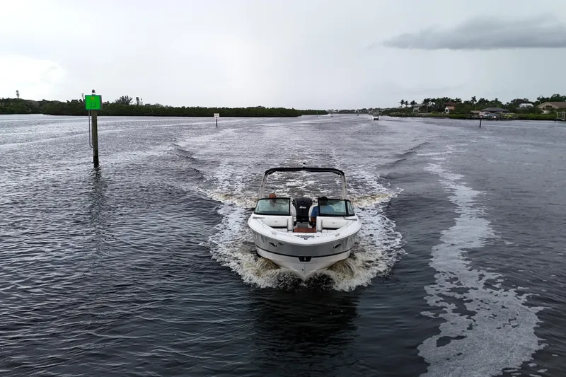 Slide: The Image of 2021 Regal LX2 boat cruising on a wide river with lush greenery. - 4