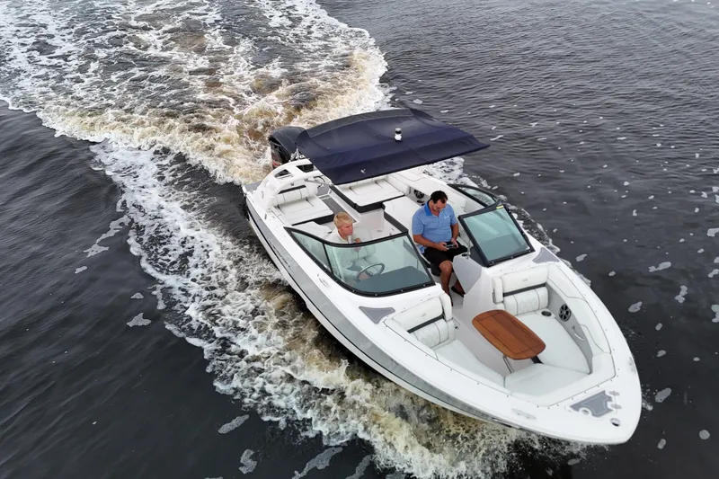 Slide: The Image of 2021 Regal LX2 boat cruising on water with two passengers under a canopy. - 5