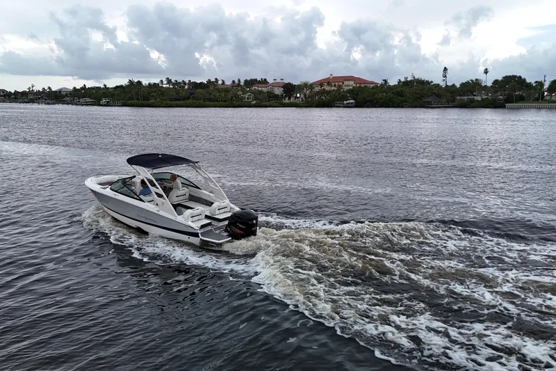 Slide: The Image of 2021 Regal LX2 boat cruising on a scenic river under cloudy skies. - 6