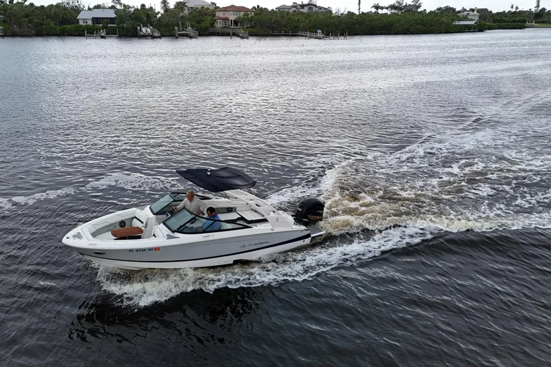 Slide: The Image of 2021 Regal LX2 boat cruising on a calm river with scenic waterfront homes. - 7