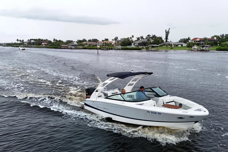 Slide: The Image of 2021 Regal LX2 boat cruising on a scenic waterway with waterfront homes. - 8