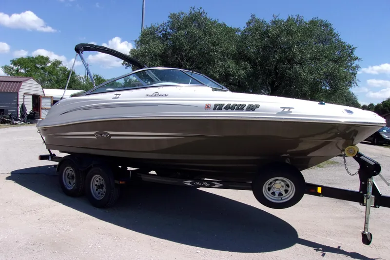 The Image of 2012 Sea Ray 200 Sundeck boat on trailer, parked outdoors under clear sky. - 1