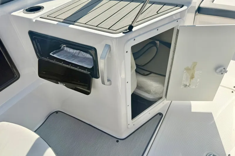 Slide: The Image of 2022 Yamaha Boats SX195 storage compartment with open door and interior view. - 26