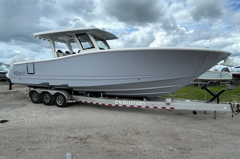 The Image of 2026 Robalo R360 Center Console boat on a trailer under cloudy skies. - 1