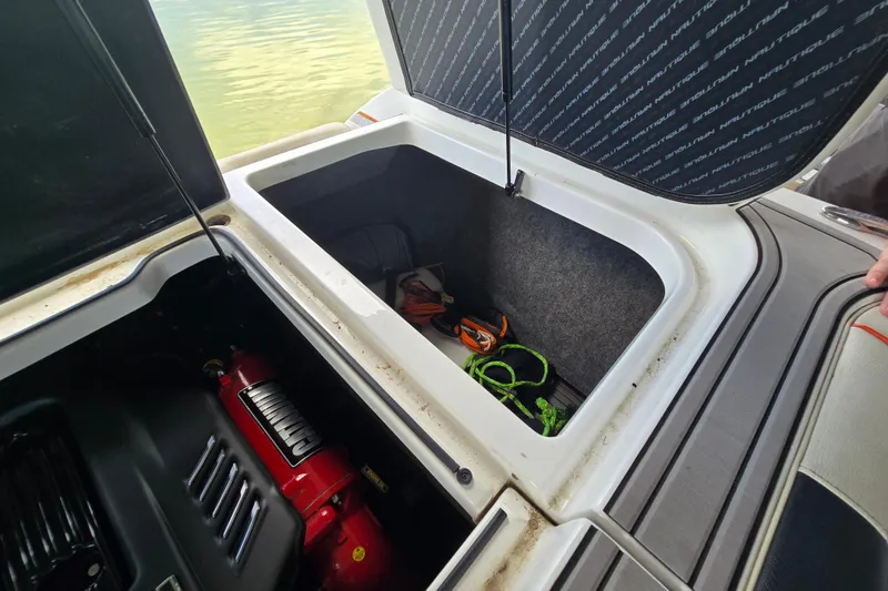 Slide: The Image of Open storage compartment on 2018 Nautique GS20 boat, showing life jackets and engine. - 21