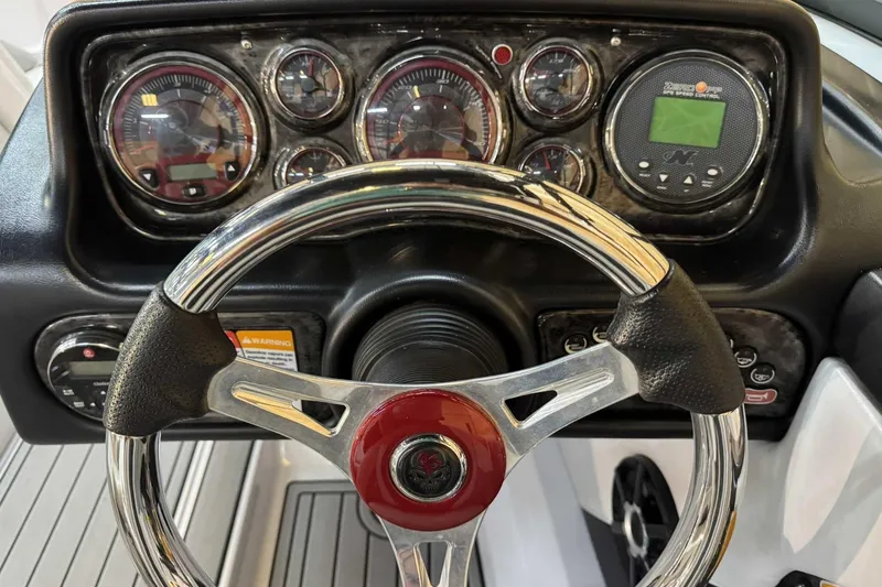 Slide: The Image of 2009 Nautique Super Air Nautique 210 Byerly dashboard with steering wheel and gauges. - 12